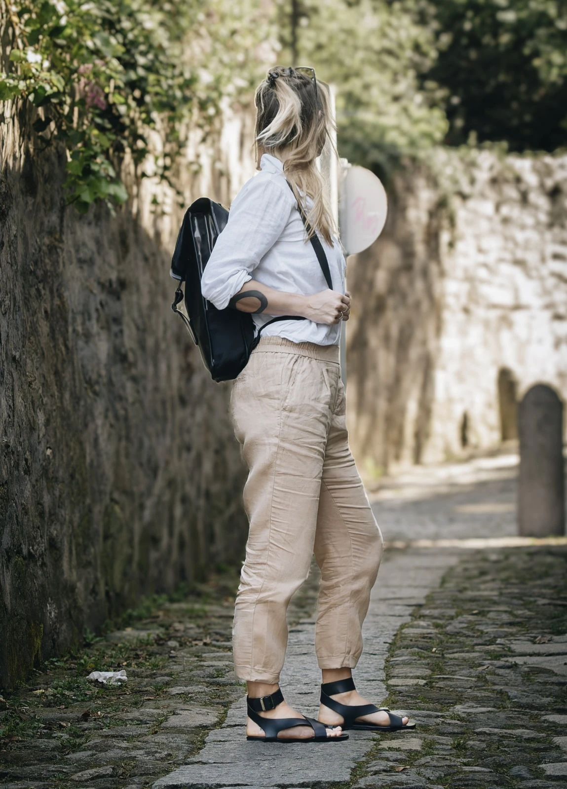 Femme marchant en sandales barefoot dans une rue pavée